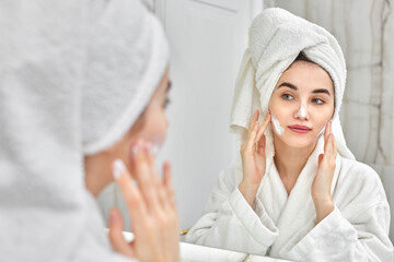 woman in white bathrobes applying apply facial cream
