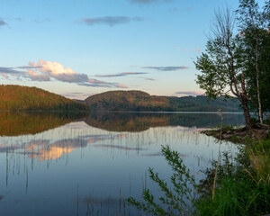 Beautiful sunset over Vågsfjärden lake in the North of Sweden. Reflections of trees and reef in...