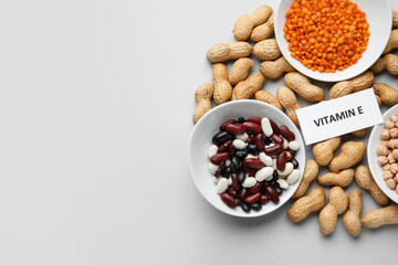 Plates with and different healthy nuts and beans rich in vitamin E on light background