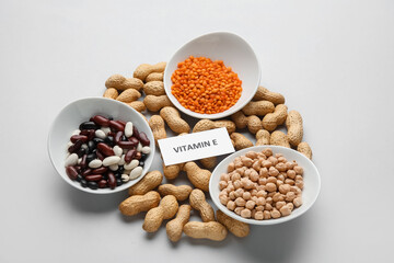 Plates with and different healthy nuts and beans rich in vitamin E on light background