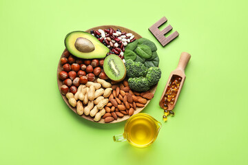 Plate with healthy products rich in vitamin E and fish oil capsules on color background