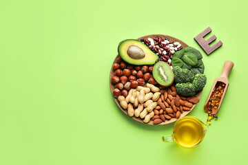 Plate with healthy products rich in vitamin E and fish oil capsules on color background
