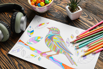 Coloring picture, headphones and pencils on wooden background