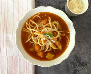 Italian minestrone vegetable soup with bacon, carrots, celery, leek, tomatoes, spaghetti noodles and parmesan.