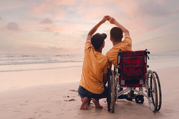 Asian special child on wheelchair on the beach with parents in family holiday to travel, exercise...