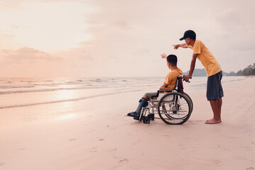 Fototapeta premium Asian special child on wheelchair on the beach with parents in family holiday to travel, exercise and learning about nature around the sea beach, Life in the education age, Happy disabled kid concept.