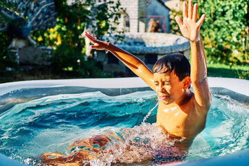 Caucasian child enjoying in the water of an inflatable pool in the garden of the house in summer