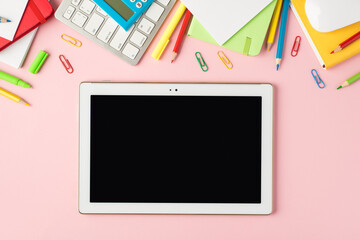 Top view photo of multicolor stationery pencils pens clips calculator diaries keyboard mouse and tablet computer display on isolated pastel pink background with copyspace