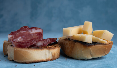 Salami and cheese with toast on a textured background. It is a concept of fast food made at home. Homemade cold cuts with delicious country toasts.
