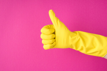 Photo of hand in yellow glove making thumb-up on isolated pink background with copyspace
