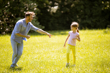 Father chasing his little daughter while playing in the park