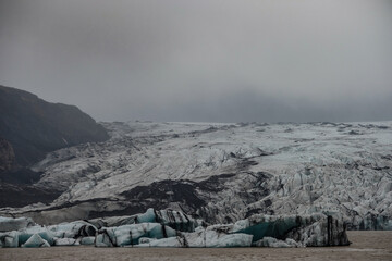 The Solheimajokull Glacier in Iceland showing icebergs and calved ice in the lagoon as ice calves...