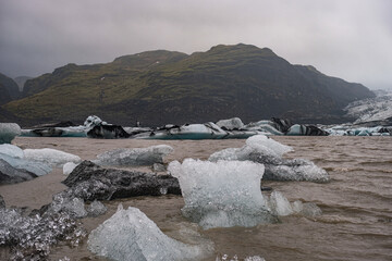 The Solheimajokull Glacier in Iceland showing icebergs and calved ice in the lagoon as ice calves...