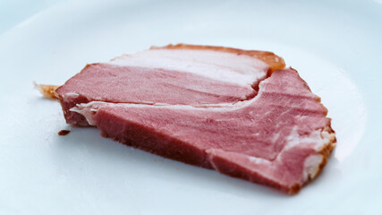 A cut piece of ham on a white insulated background. A piece of prosciutto, ham. Meat, eating an isolated white background