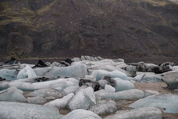 The Solheimajokull Glacier in Iceland showing icebergs and calved ice in the lagoon as ice calves...