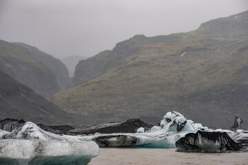 The Solheimajokull Glacier in Iceland showing icebergs and calved ice in the lagoon as ice calves...