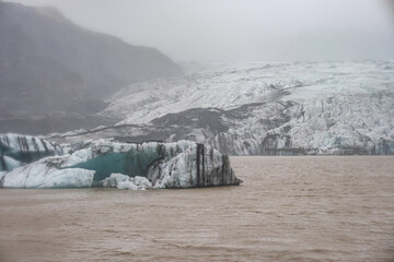 The Solheimajokull Glacier in Iceland showing icebergs and calved ice in the lagoon as ice calves...