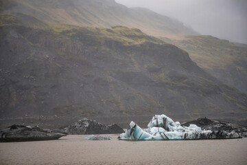 The Solheimajokull Glacier in Iceland showing icebergs and calved ice in the lagoon as ice calves...