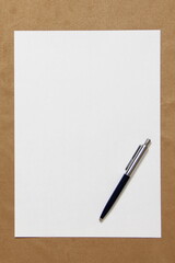 Template of white paper with pen lies on light brown cloth background. Concept of business plan and strategy. Stock photo with empty space for text and design.