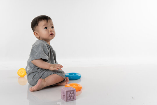 Portrait image adorable and cute happy Asian Chinese baby boy playing alone on white background