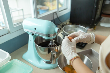 Closeup of woman, female baker hands is cracking an eggs, preparing bakery material to bake homemade cake or bakery first time, learning new skills when home quarantine, COVID-19 or Coronavirus spread