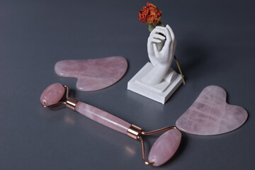 Gua Sha massager and jade roller on grey background. Pink jade stone for face and body care. Minimalist Aesthetic