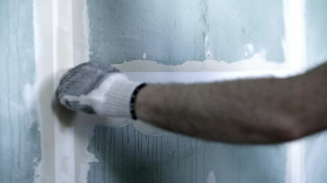 Worker Glues Plasterboard Joint With Paper Tape