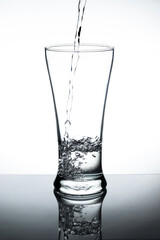Water pour into the glass on white background