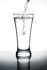 Water pour into the glass on white background