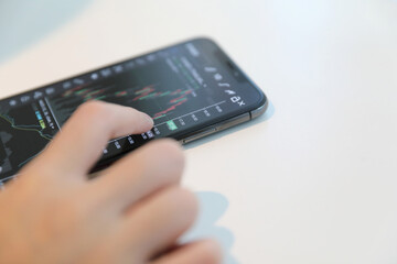 Female hand with smartphone trading stock online in coffee shop , Business concept