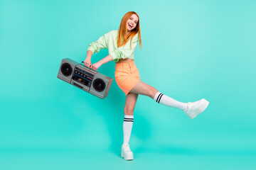Full length body size photo pretty red haired girl dancing keeping retro tape recorder isolated vivid turquoise color background