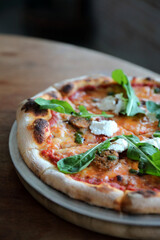 Italian Sausage and rocket salad pizza on wood background