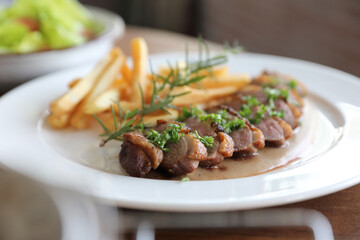 Duck magret confit with chips on wood table