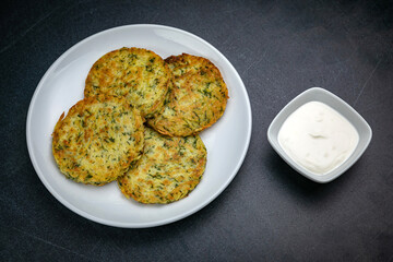 Draniki with sour cream on a dark table
