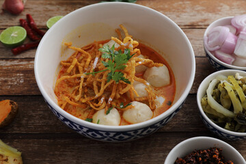 Local northern Thai food Egg noodle curry with meatballs on wood background