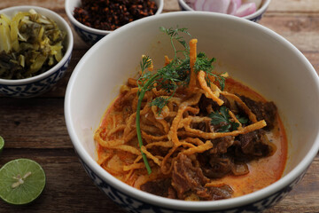 Local northern Thai food Egg noodle curry with beef on wood background