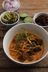 Local northern Thai food Egg noodle curry with beef on wood background