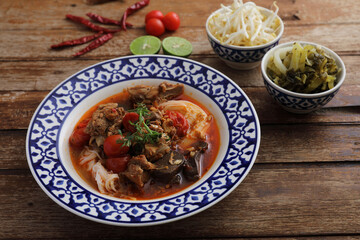 Local northern thai food Rice noodles with pork in spicy soup in wood background