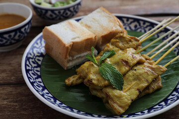 Local Thai food pork satay with oeanut dipping sauce isolated in wood background