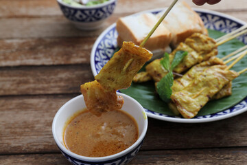Local Thai food pork satay with oeanut dipping sauce isolated in wood background