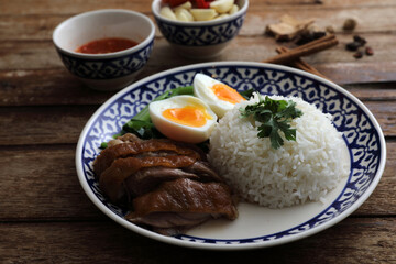 Local Thai food stewed pork leg on rice isolated in wood background