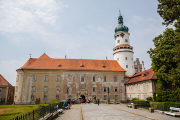 Obraz premium Baroque romantic castle Nove mesto nad Metuji, renaissance chateau with round white clock tower, red tile roof, arched portal entrance, summer sunny day Eastern Bohemia, Czech Republic