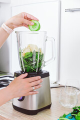 Young woman is preparing healthy food on light kitchen. Green healthy food concept. Healthy lifestyle, less weight concept, detox smoothie at home