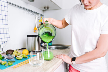 A woman is preparing a homemade detox juice or concentrated vitamin smoothie in blender. Healthy lifestyle, healthy sports nutrition.