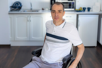 Smiling Young Handicapped Man Sitting On Wheelchair In Kitchen