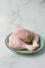raw chicken leg without skin over a green plate and herbs. green background