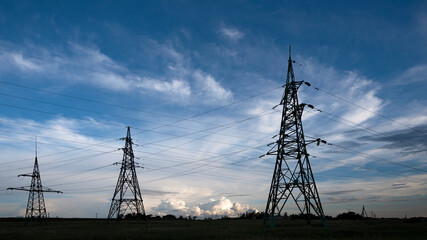 Power lines and sky with clouds.Wires over the fields.Powerful lines of electric gears.Field and aerial lines, silhouettes at dusk.