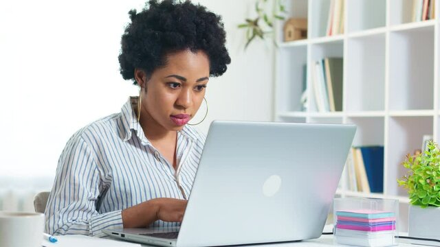 Portrait of African American young woman working on laptop remotely. Black girl student is studying online using a computer. Female freelancer. 4K.