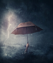 Human hand holding an umbrella sinking in the ocean. Surreal and dramatic scene of person drowning in the sea waters under the storm. Business despair and failure metaphor. Crisis problems concept - obrazy, fototapety, plakaty