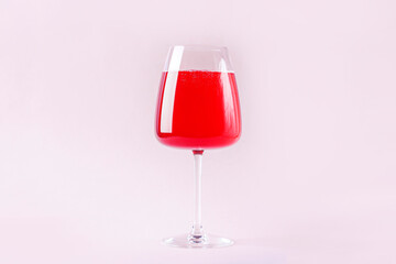 Still life with red refreshing summer alcoholic cocktail drink with strawberry in wine glass on pink background. Fruit or berry wine. Minimalism